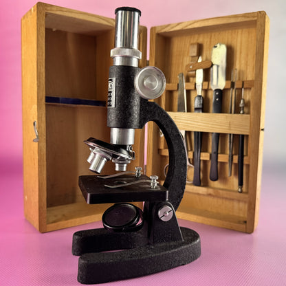 Vintage microscope in a wooden case on a pink background