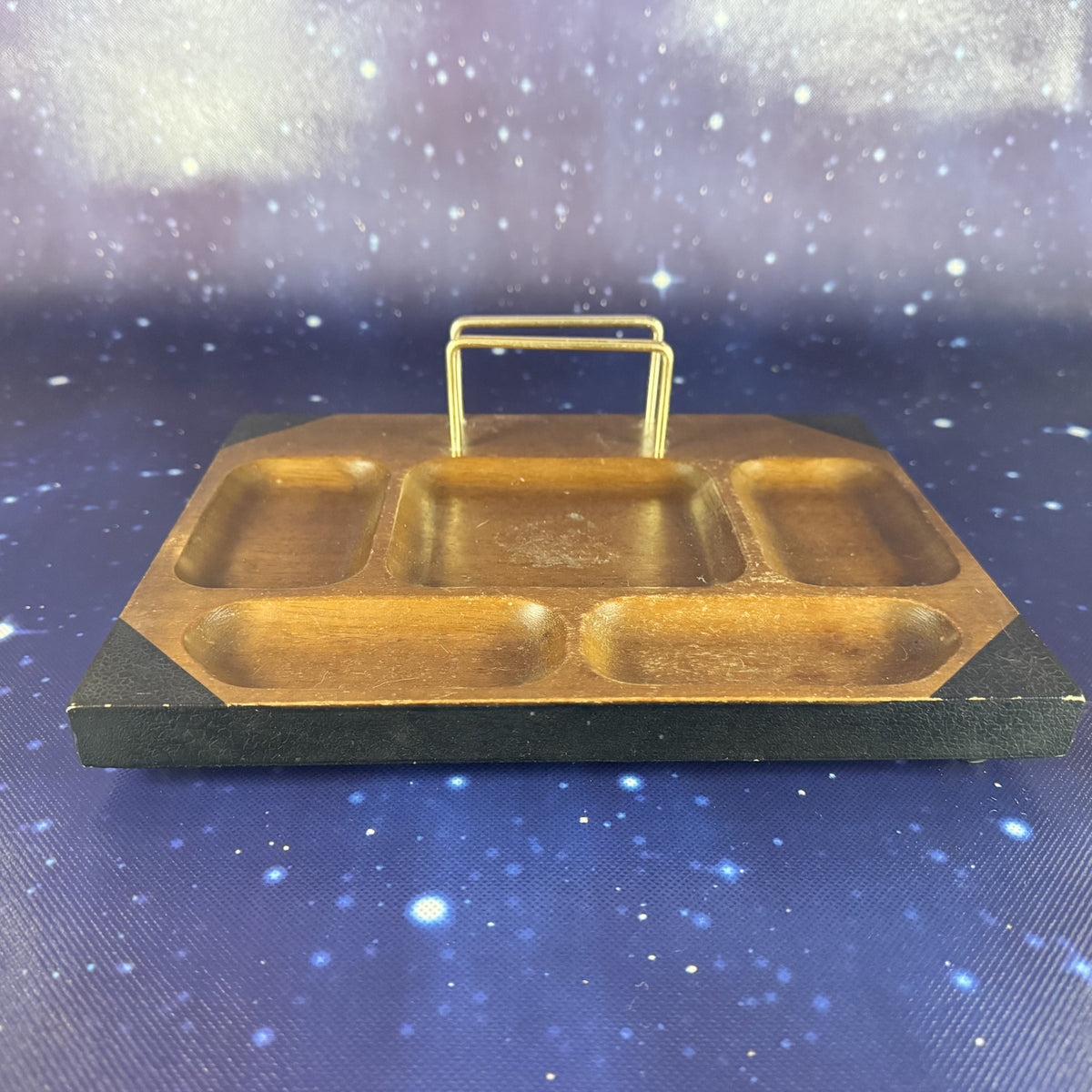 Gold-colored metal tray with a handle on a blue textured background