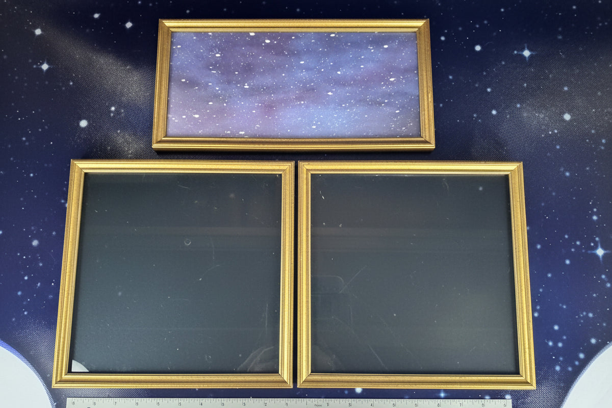 Three gold-framed mirrors on a dark blue background with a ruler at the bottom.