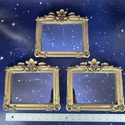 Three ornate gold picture frames on a blue background with a ruler for scale.