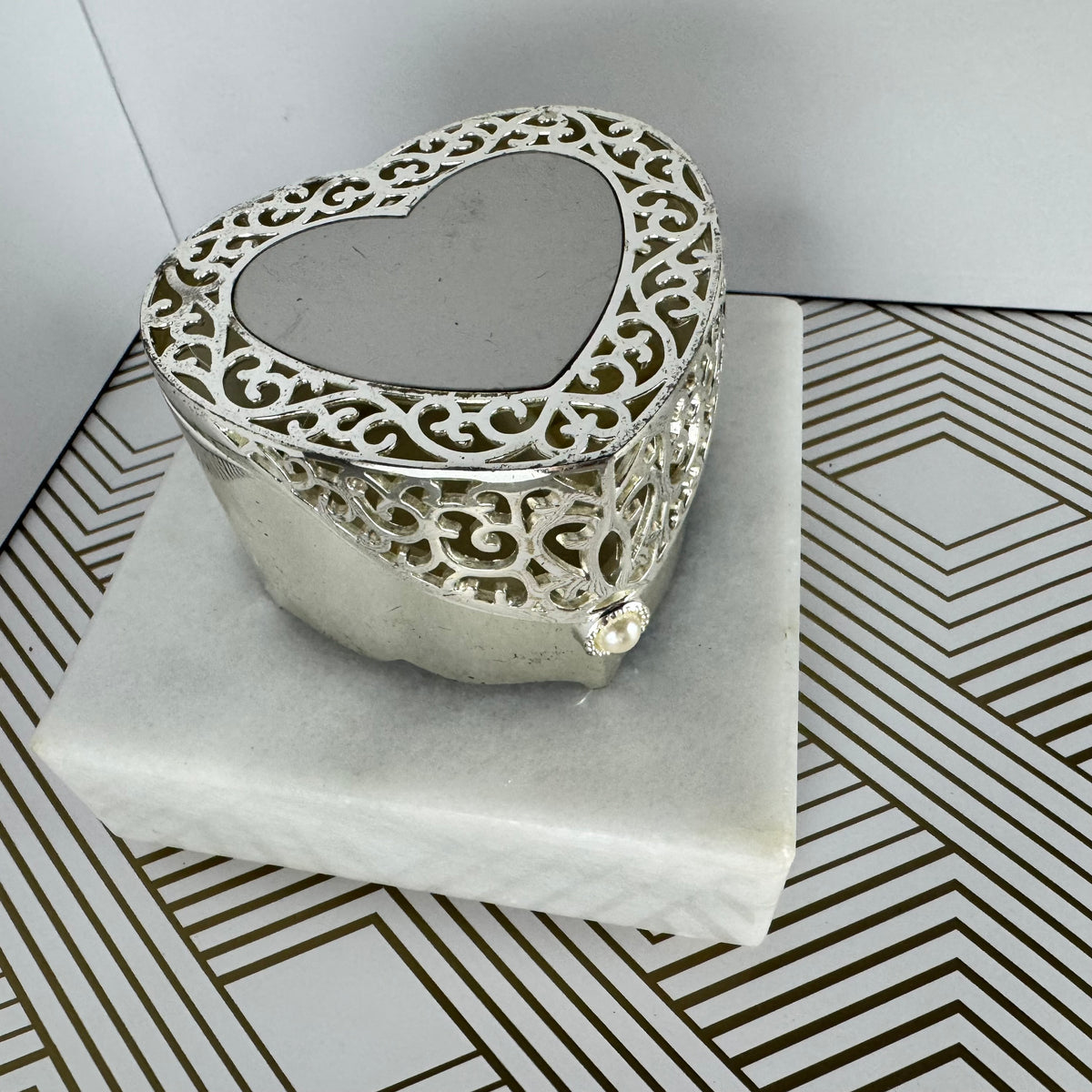Silver-toned, heartshaped jewelry box with faux pearl clasp. Velvet-lined interior.