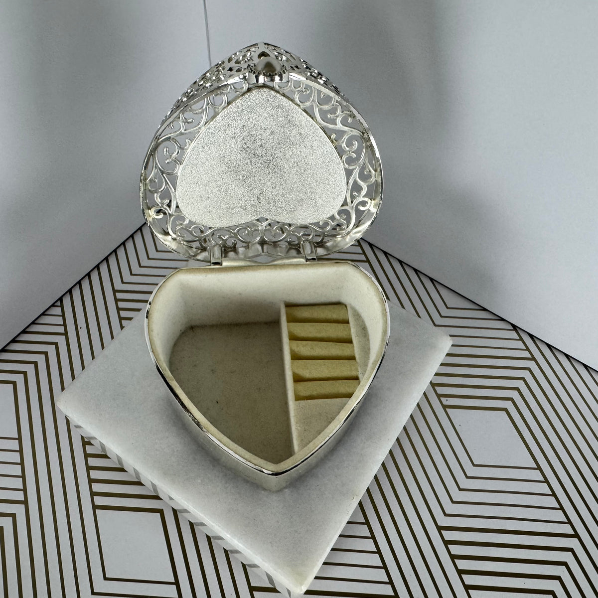 Silver-toned, heartshaped jewelry box with faux pearl clasp. Velvet-lined interior.