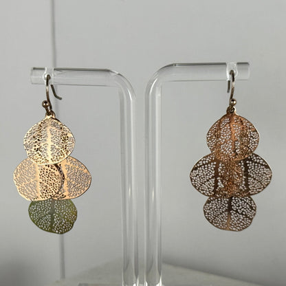 Pair of gold earrings on clear stands against a gray background
