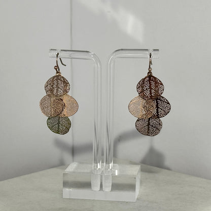 Pair of layered earrings on a clear stand against a neutral background