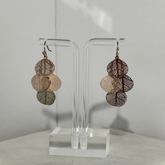 Pair of layered earrings on a clear stand against a neutral background