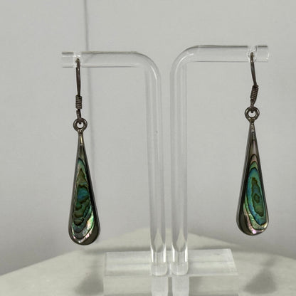 Teardrop-shaped earrings with green and black pattern on a clear stand against a white background