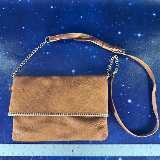 Brown leather handbag with chain strap on a blue starry background