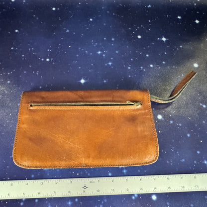 Brown leather clutch with gold zipper on a starry background