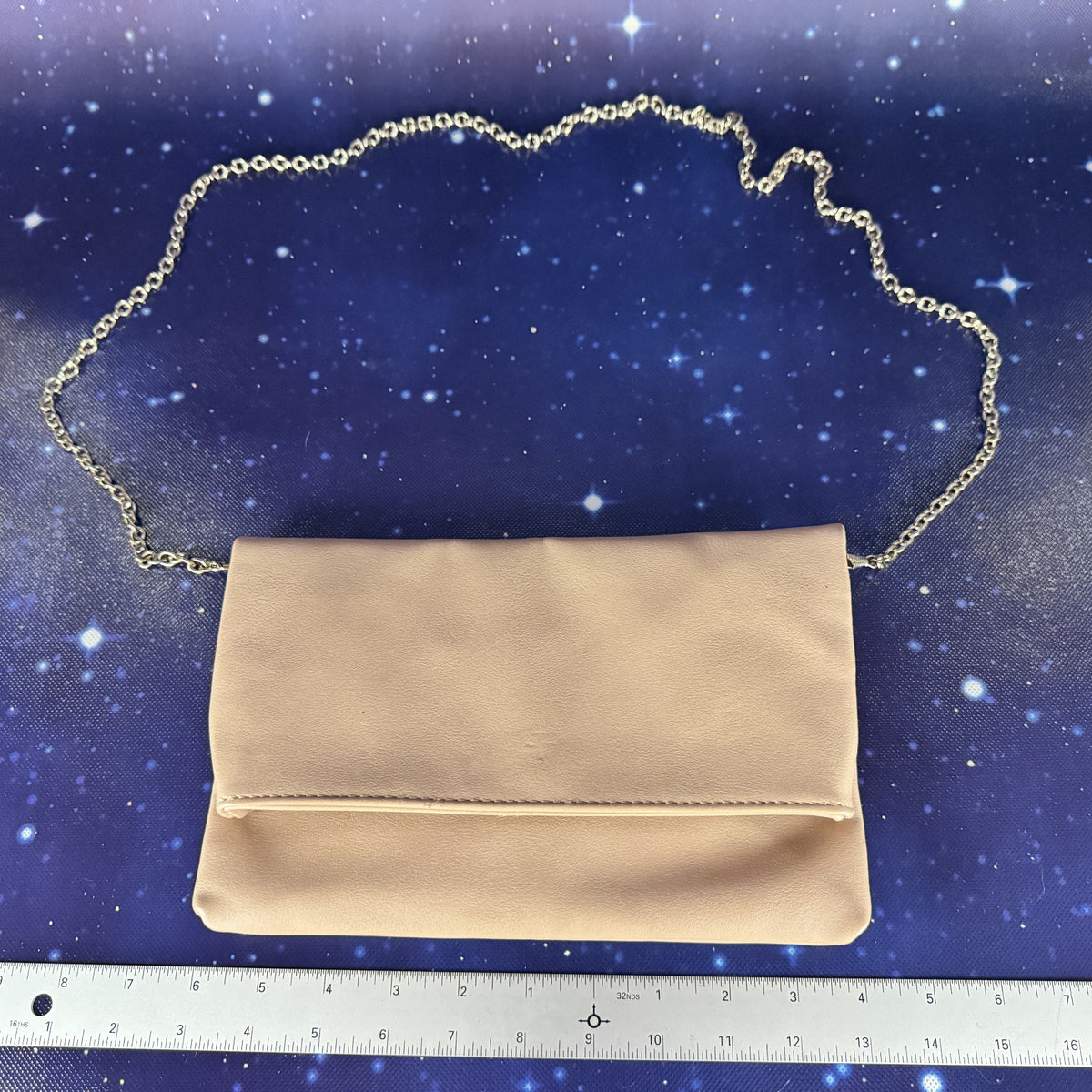 Beige handbag with gold chain on a starry night sky background