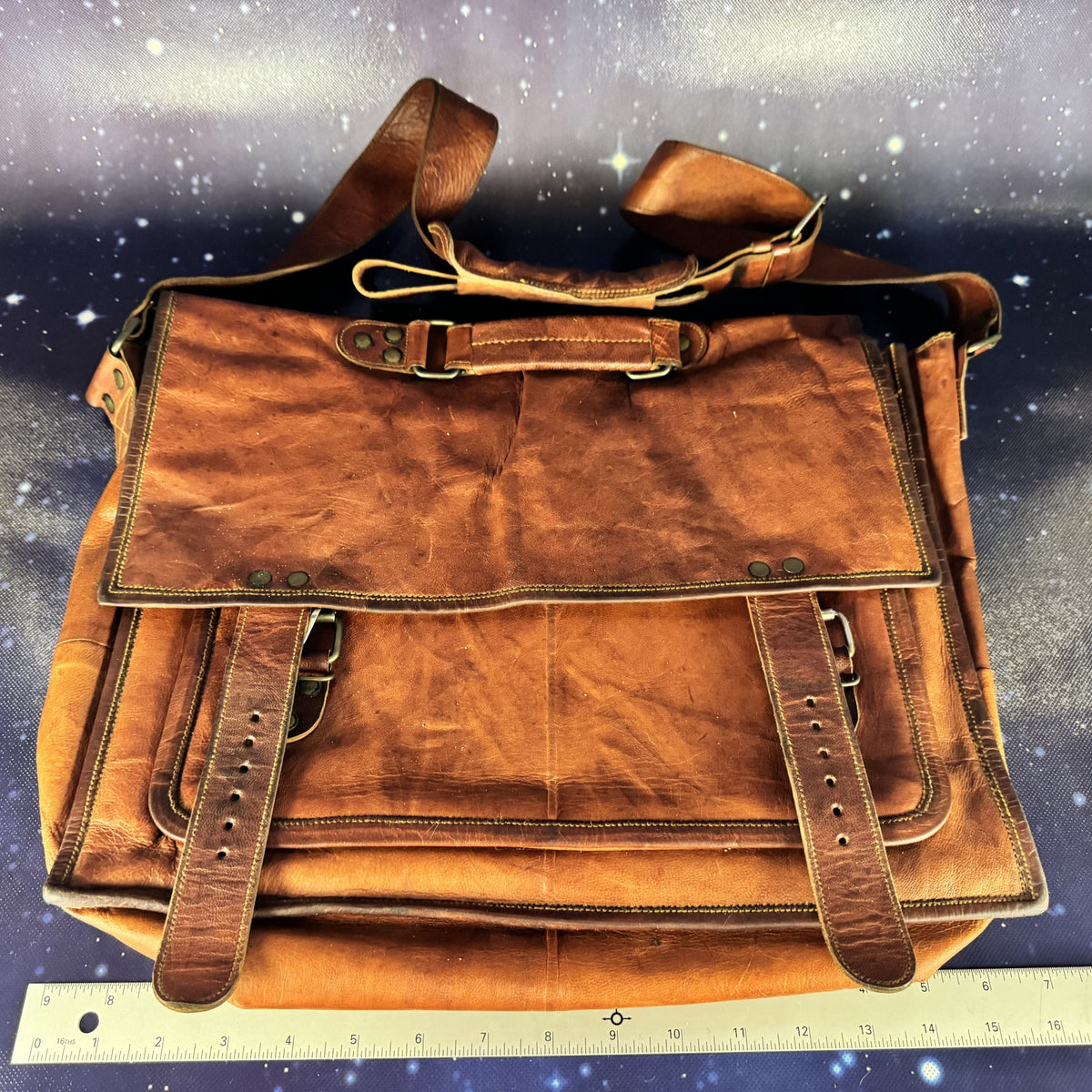 Brown leather bag on a starry night sky background with a ruler at the bottom.