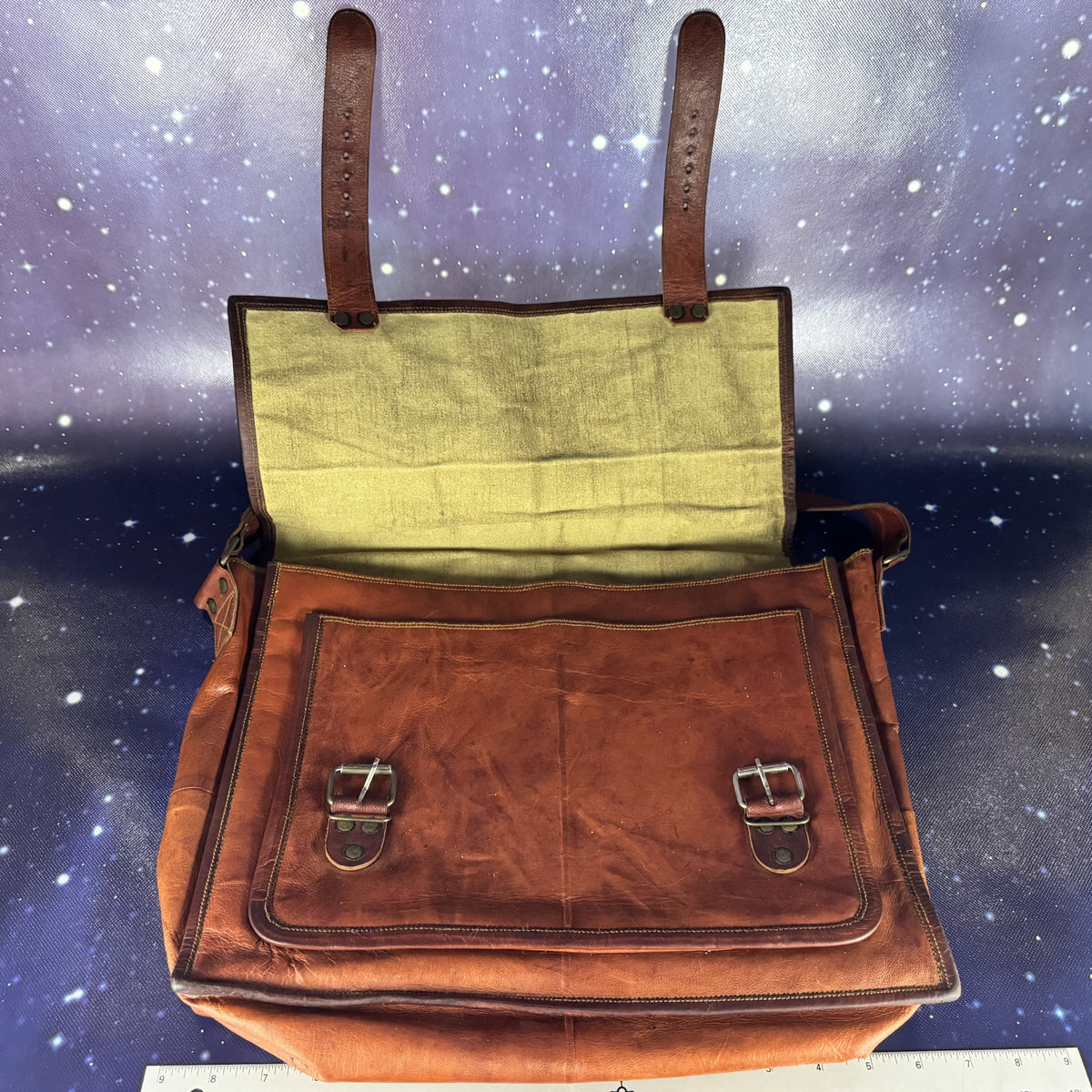 Brown leather bag with green interior against a starry space background