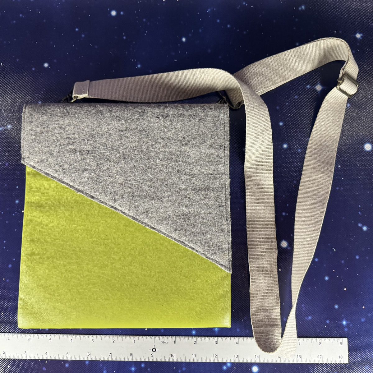 Crossbody bag with gray top half and green bottom half on a starry night background with a ruler at the bottom.