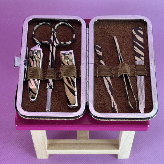 Manicure set with zebra pattern on a pink stand against a purple background